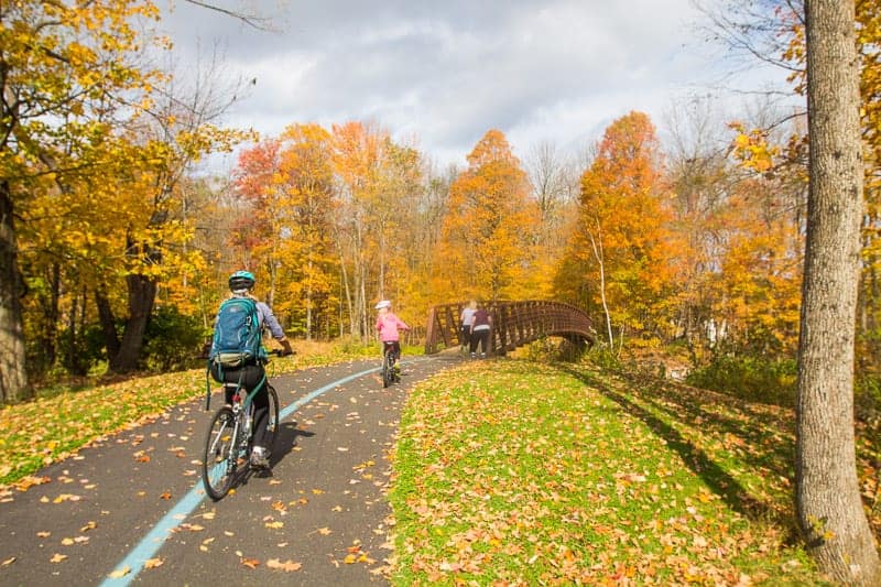 family riding bikes on the Stowe Recreation Path in the fall