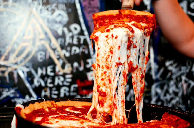 a slice of deep dish pizza oozing with cheese