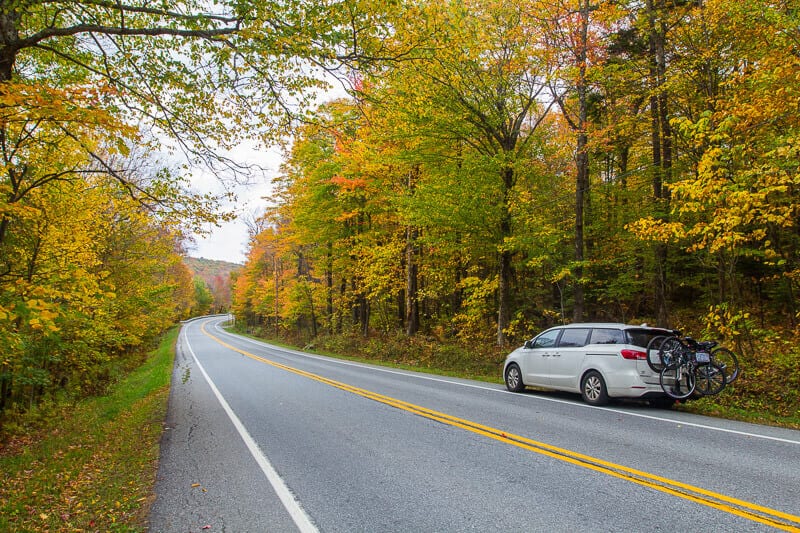 minvan on side of road lined with fall foliage