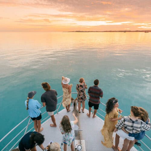 people on boat looking for whales at sunset