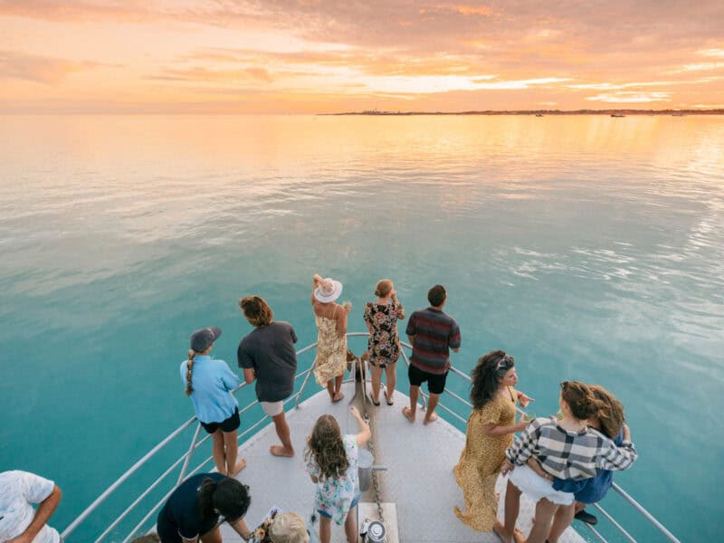 people on boat looking for whales at sunset