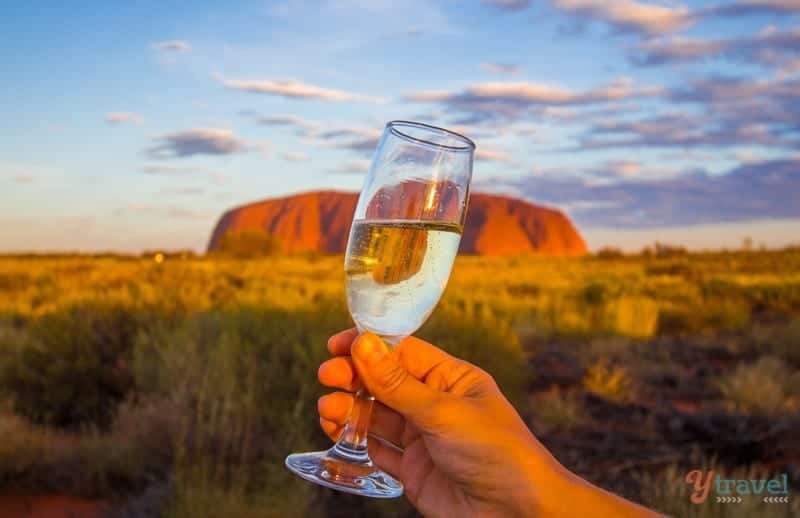 glass of champagne in front of uluru